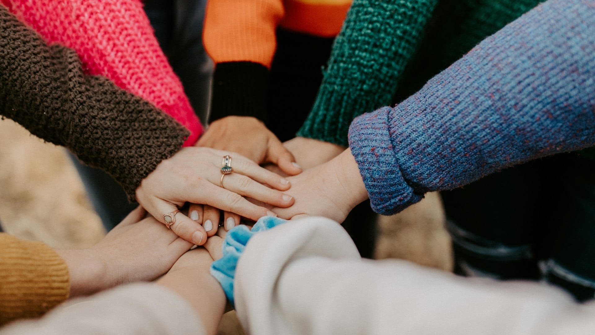 A circle of people joining their hands together.